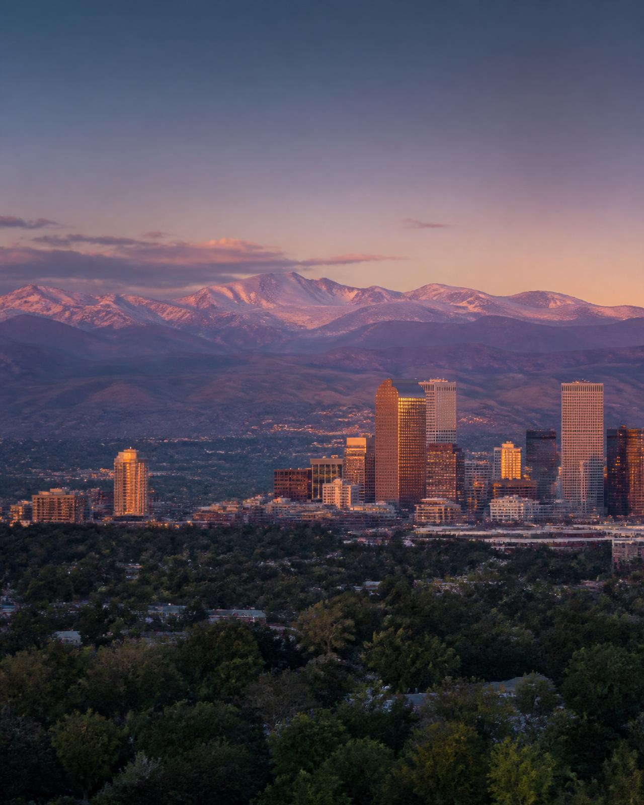 Denver, Colorado skyline at dusk with the Rocky Mountains behind